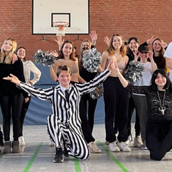 Die Schüler*innen des Tanzkurses posieren in der Sporthalle für ein Abschlussfoto nach ihrer Performance.