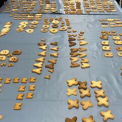 Viele Plätzchen in Buchstabenform auf einem langen Tisch.