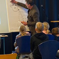 Ein Künstler zeichnet eine Figur mit Edding auf ein Flipchart.